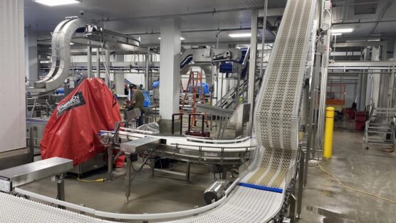 Long automated filling and labeling line inside a high-volume manufacturing facility with palletized finished goods staged at the end of the run