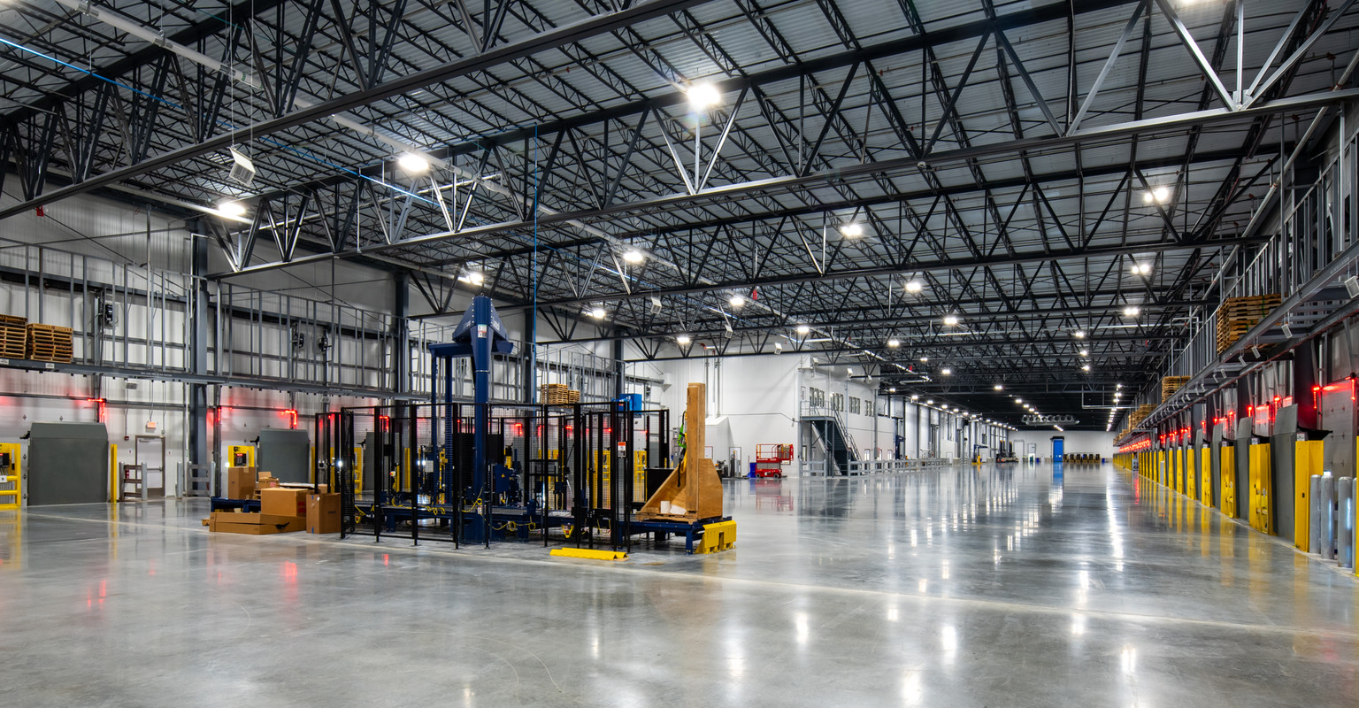 Wide interior of a Primus-built cold storage facility with a long dock line and automated wrapping equipment on the floor
